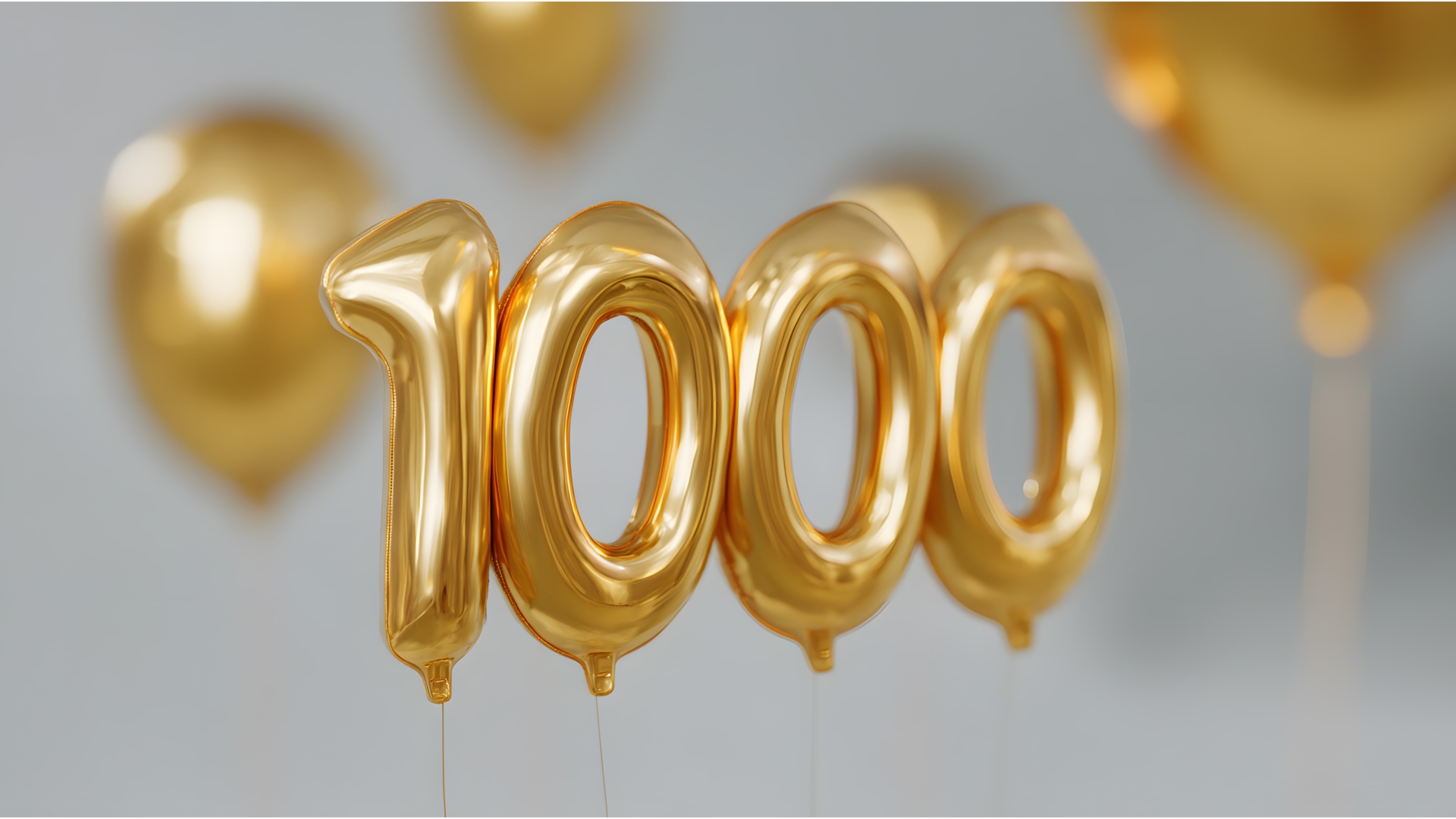 Goldene Luftballons in Form der Zahl „1000“ schweben vor einem neutralen Hintergrund. Im unscharfen Hintergrund sind weitere goldene Ballons zu sehen – das Bild vermittelt festliche Stimmung und Jubiläumsfreude.
