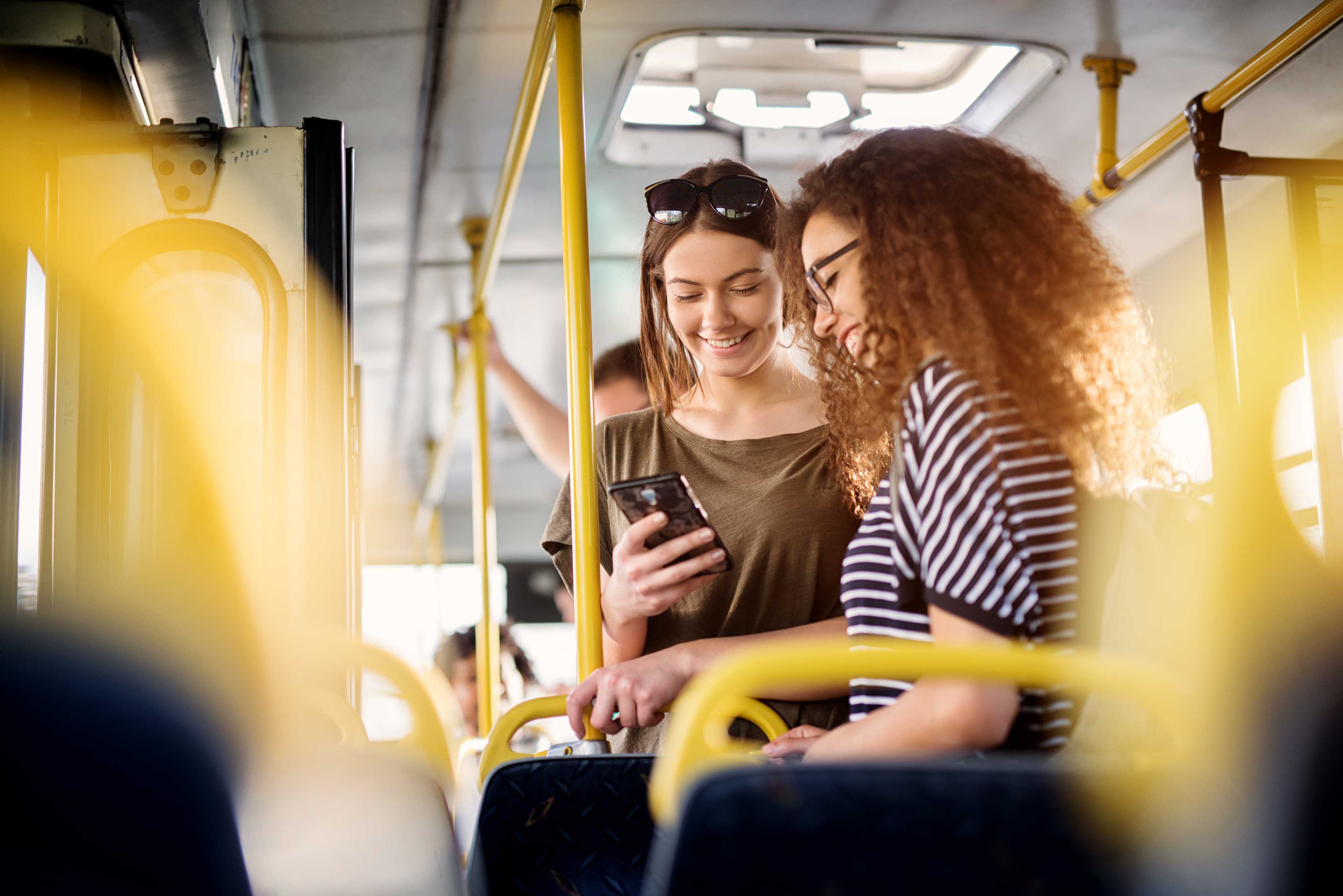 Two,Cheerful,Pretty,Young,Women,Are,Standing,In,A,Bus Two,Cheerful,Pretty,Young,Women,Are,Standing,In,A,Bus