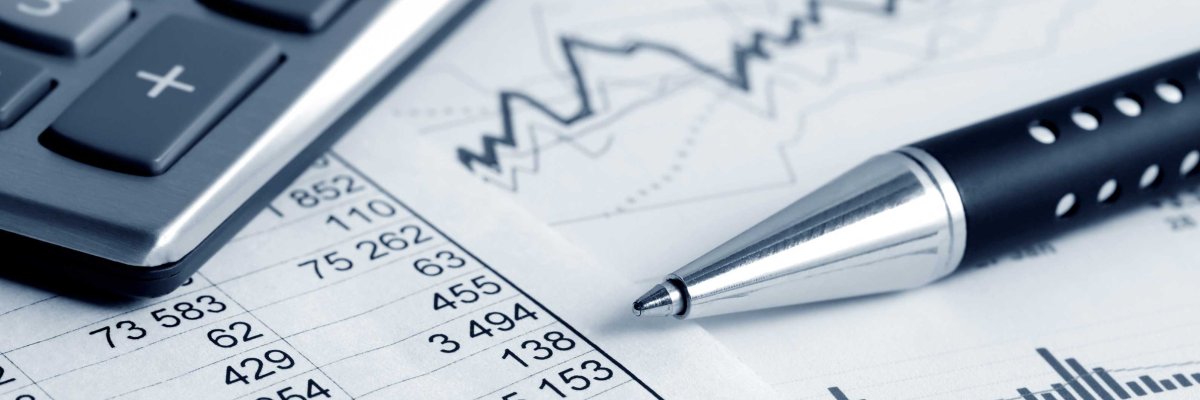 Ein Taschenrechner, ein silberner Stift und Finanzdokumente mit Tabellen und Diagrammen liegen auf einem weißen Schreibtisch. Das Bild symbolisiert Finanzanalyse oder Buchhaltung.