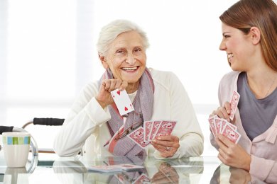 Young,Woman,Playing,Cards,With,A,Happy,Elderly,Woman,In Young,Woman,Playing,Cards,With,A,Happy,Elderly,Woman,In